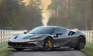 Szary Ferrari SF90 z żółtymi akcentami na tle jesiennego krajobrazu.