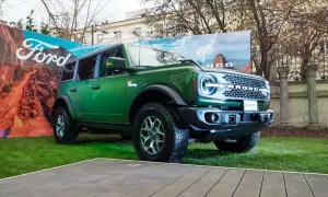 Zielony Ford Bronco prezentuje się imponująco na tle krajobrazu z pustynią i logo Ford.
