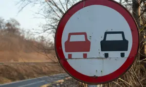 Znak drogowy zakaz wyprzedzania. Czerwony i czarny samochód na białym tle, otoczone czerwoną obwódką.