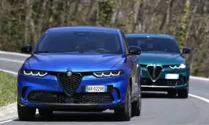 Dwa Alfa Romeo Tonale, jeden niebieski, drugi zielony, jadą drogą. Sprawdź alfa romeo tonale cena!