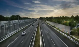 Szeroka autostrada A2 z ruchem samochodowym, otoczona zielenią i ekranami akustycznymi.