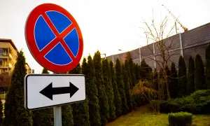 Znak zakaz parkowania z tabliczką wskazującą kierunki.