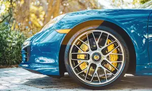 Błękitne Porsche z żółtymi zaciskami hamulcowymi. Felga ma ciekawy rozstaw śrub, podkreślający sportowy charakter auta.
