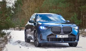 Niebieskie BMW X3 na śniegu. Zbliżenie na przód auta, gdzie widać charakterystyczny grill i światła. Idealne do sprawdzenia bmw x3 wymiary w zimowych warunkach.