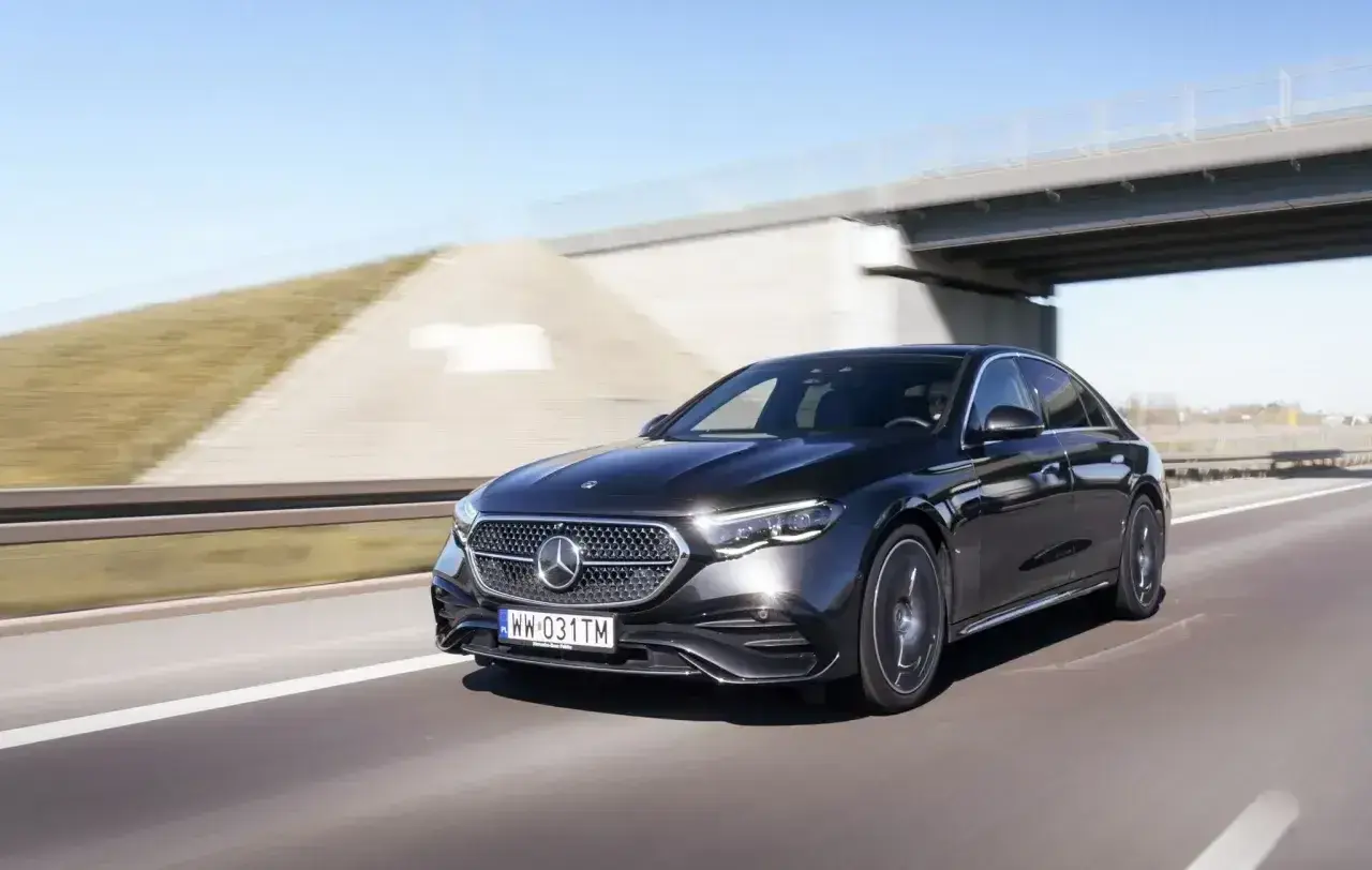Elegancki, czarny Mercedes E220d pędzi autostradą pod mostem.