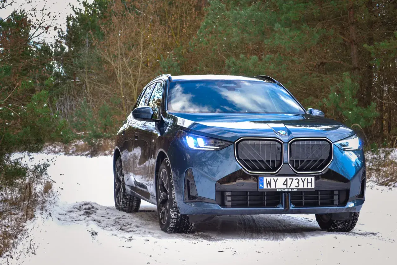 Niebieskie BMW X3 na śniegu. Zbliżenie na przód auta, gdzie widać charakterystyczny grill i światła. Idealne do sprawdzenia bmw x3 wymiary w zimowych warunkach.