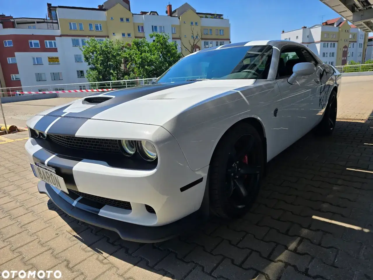 Biały Dodge Challenger z czarnymi pasami, idealny na letnie przejażdżki. Sprawdź jego atrakcyjną dodge challenger cena!