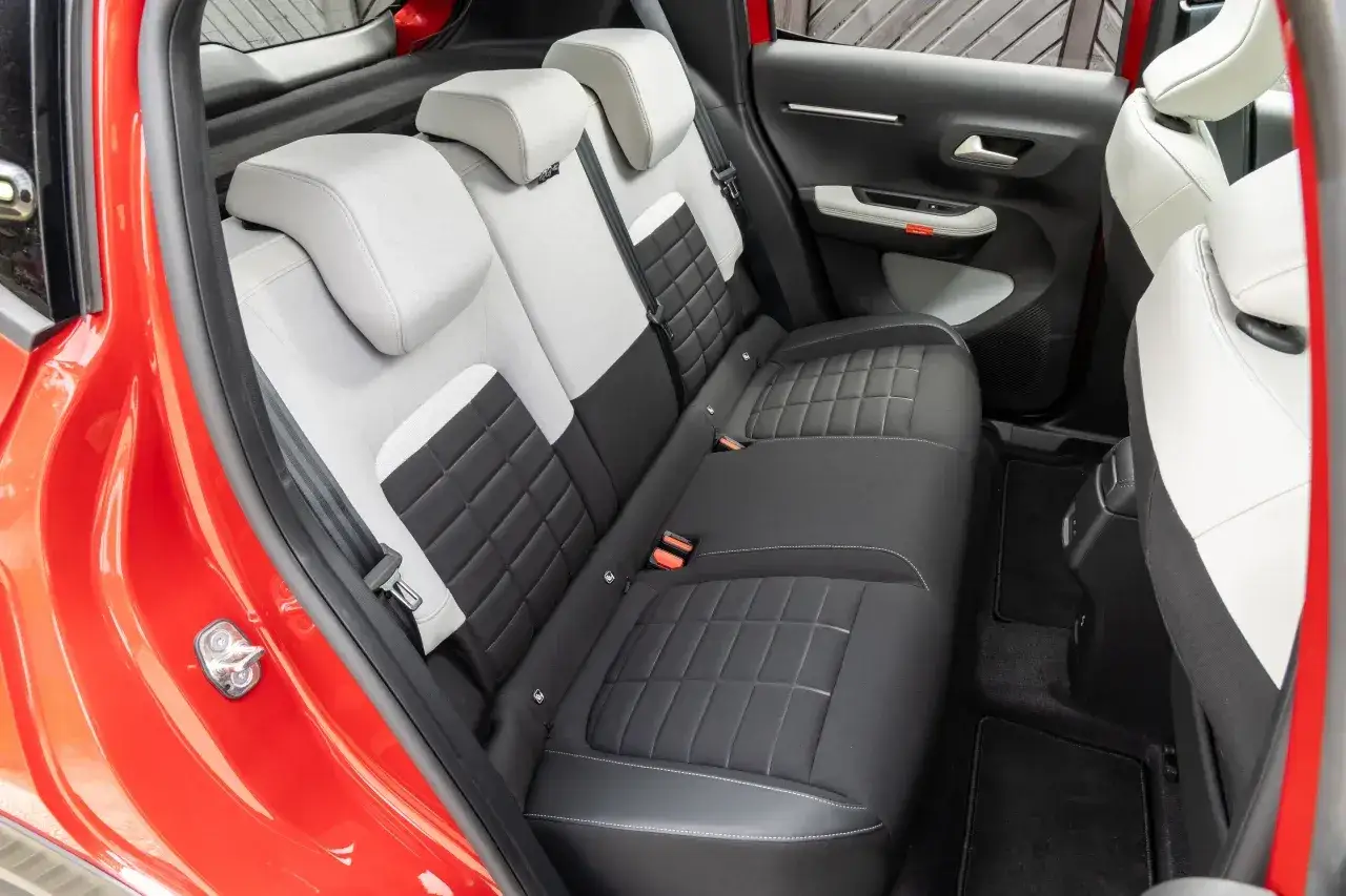 Tylne siedzenia Citroëna C3 w dwukolorowej tapicerce, z pikowanymi wstawkami i czerwonymi akcentami.