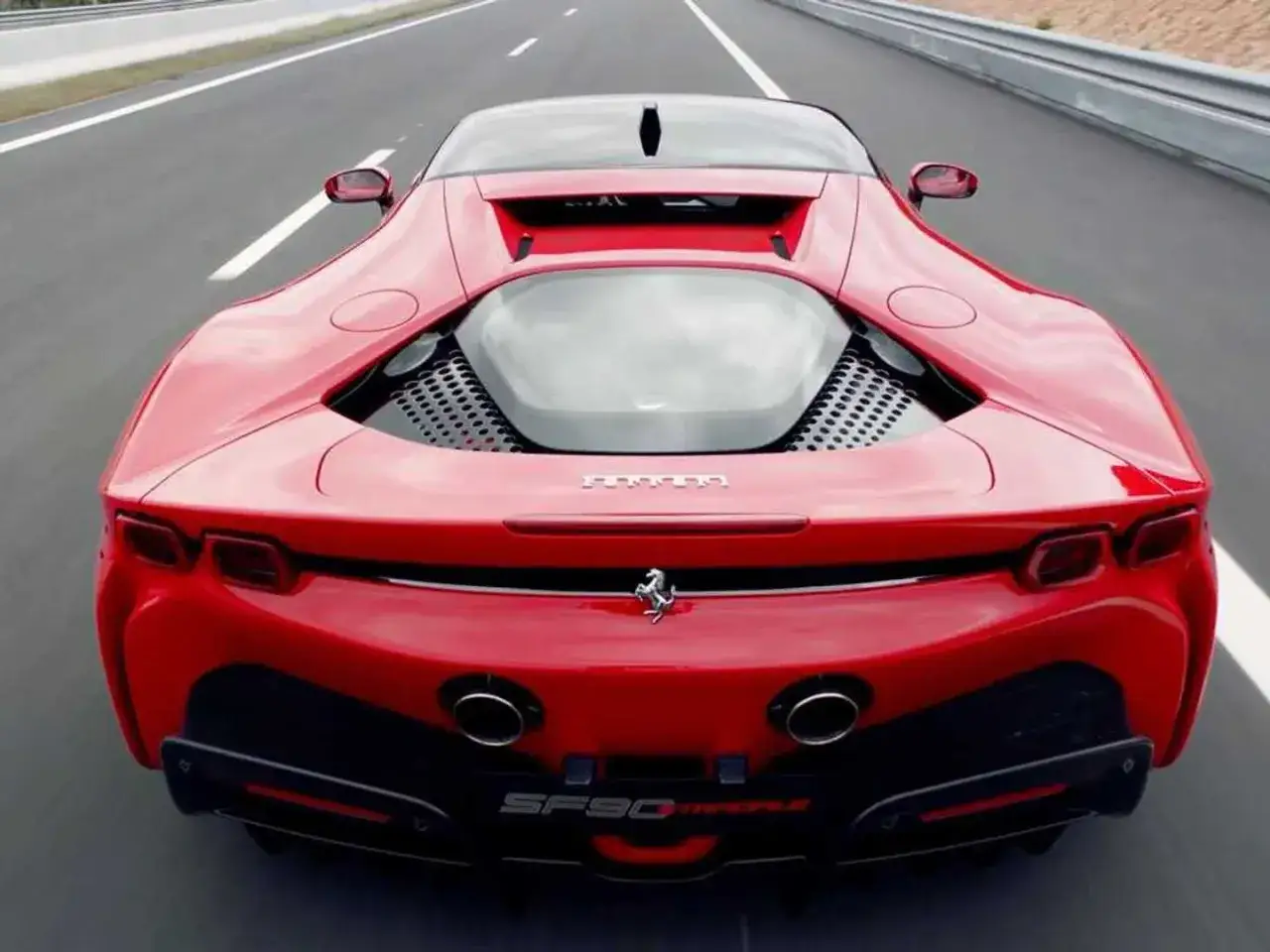 Czerwone Ferrari SF90 Stradale pędzi po pustej drodze, ukazując swoje agresywne tylne linie i potężne detale.