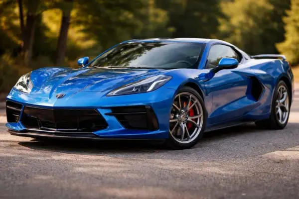 Błękitny Chevrolet Corvette Stingray z czerwonymi zaciskami hamulcowymi na tle drzew.