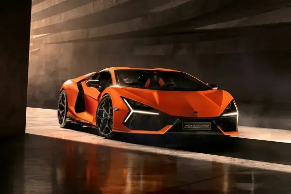 Pomarańczowy Lamborghini Revuelto, którego cena jest astronomiczna, błyszczy w półmroku.