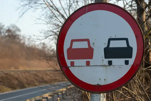 Znak drogowy zakaz wyprzedzania. Czerwony i czarny samochód na białym tle, otoczone czerwoną obwódką.