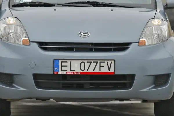 Przód szarego samochodu z widocznym logo Daihatsu i tablicą rejestracyjną EL 077FV.