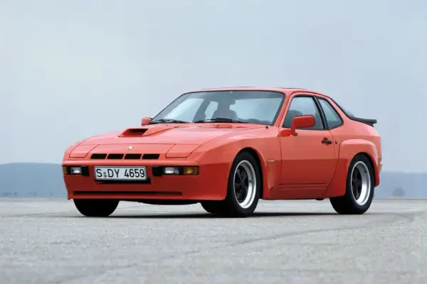 Pomarańczowy Porsche 924 Targa z lat 80. na pustej drodze.