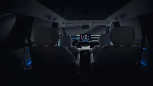 Wnętrze nowego Toyota Highlander nocą, z niebieskim nastrojowym oświetleniem i dużym ekranem multimedialnym.