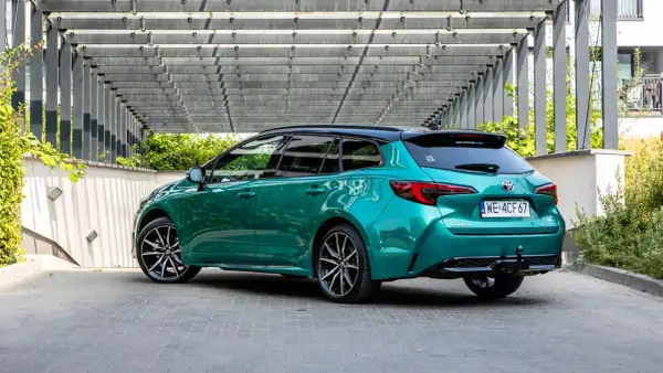 Zielona Toyota Corolla kombi z czarnym dachem, zaparkowana pod nowoczesną pergolą. Sprawdź atrakcyjną toyota corolla cena!