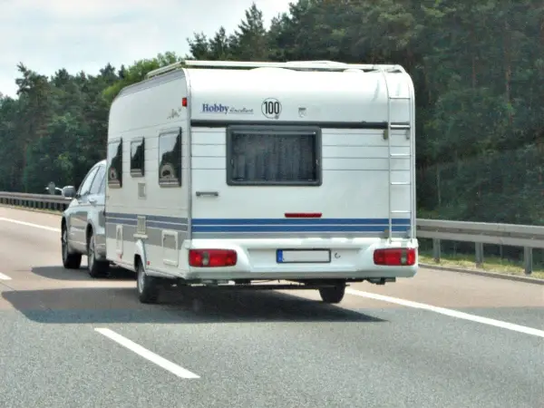 Samochód ciągnie przyczepę kempingową Hobby Excellent. Kierowca z kodem 96 prawo jazdy cieszy się podróżą.