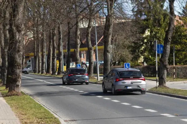 Dwa samochody z literą "L" na dachu, przygotowujące się do egzaminu praktycznego na prawo jazdy. Zastanawiasz się, ile kosztuje egzamin praktyczny na prawo jazdy?
