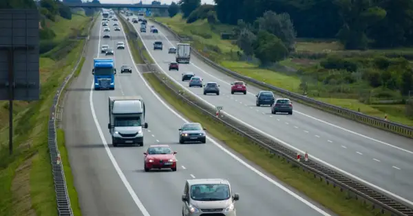 Na autostradzie ruch samochodów. Niebieska ciężarówka wykonuje wyprzedzanie z prawej strony, omijając inne pojazdy.