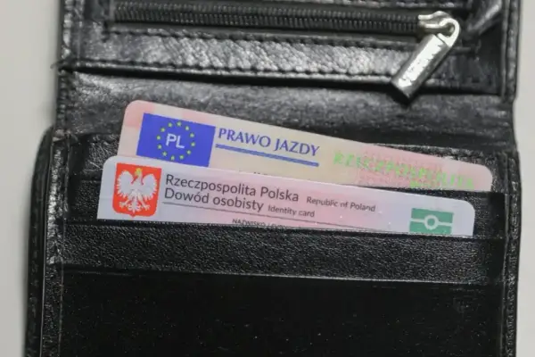 Czarny portfel z polskim dowodem osobistym i prawem jazdy. Na dokumencie prawa jazdy widnieje napis "prawo jazdy" oraz symbol UE. Na dowodzie osobistym widnieje godło Polski i napis "Rzeczpospolita Polska". Prawo jazdy ograniczenia 71.