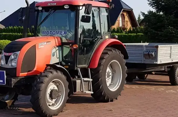 Czerwony Zetor z przyczepą, gotowy do pracy. Posiadanie prawa jazdy na traktor otwiera drogę do takich maszyn.